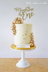 Tall off white cake with golden baubles Tall off white cake with golden baubles